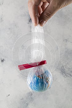 Human hand holds the planet earth in a plastic bag