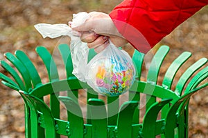 The human hand holds the planet earth in a plastic bag above the trash can. Hand putting Earth globe in trash bin. The concept of