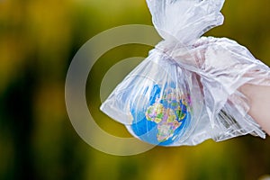 The human hand holds the planet earth in a plastic bag. The concept of pollution by plastic debris. Global warming due to