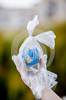 The human hand holds the planet earth in a plastic bag. The concept of pollution by plastic debris. Global warming due to
