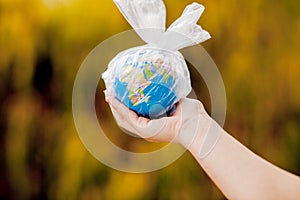 The human hand holds the planet earth in a plastic bag. The concept of pollution by plastic debris. Global warming due to