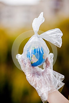 The human hand holds the planet earth in a plastic bag. The concept of pollution by plastic debris. Global warming due to