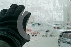 Human hand on the icy glass of the car with snow patterns