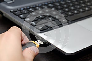 Human hand inserting USB flash drive into laptop computer close up