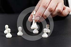 A human hand moving King chess piece at table