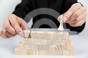 A human hand moving King chess piece at table