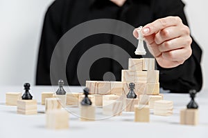 A human hand moving King chess piece at table