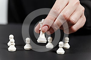 A human hand moving King chess piece at table