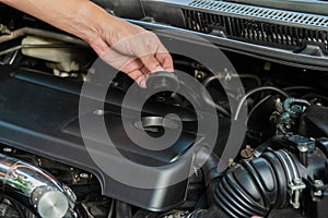 Human hand is opening the car engine oil cap to check the machine