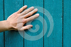 human hand palm on vertical green wooden planks with peeling paint, texture close-up