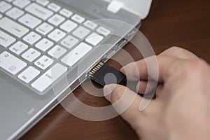 Human hand plugging in an SD media card into the personal laptop computer.