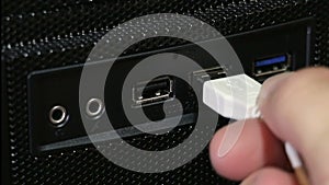 Human hand plugging white usb cable in port on front panel of PC