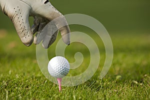 Human hand positioning golf ball on tee, close-up photo