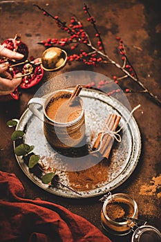 Human hand pouring cinnamon to turkish hot drink salep