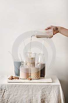 Human hand pouring fresh almond dairy free milk from bottle