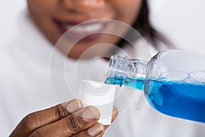 Human Hand Pouring Mouthwash Into Bottle Cap