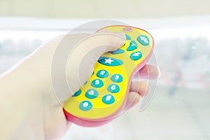The human hand presses the control buttons of the TV children`s yellow bright remote control at leisure with your finger to chang