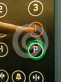 Human hand pressing the 1st floor button in the elevator