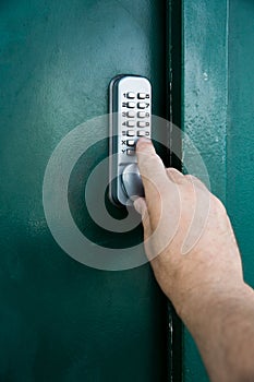 A human hand pressing the buttons on a combination lock to gain entry to a secure door