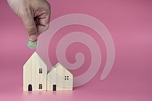 A human hand put a coin in the model house. Ideas for saving money to buy a new home and loans for planning future real estate