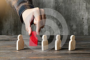 A human hand put one wooden figure to the row of wooden figures