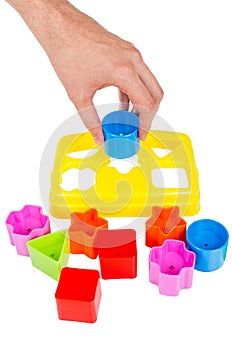 Human hand puts wrong shape into shape sorter toy isolated photo
