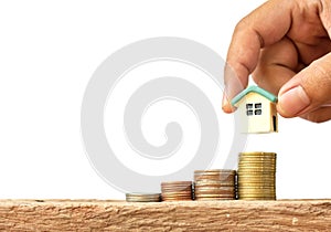 Human hand putting house model on coins stack