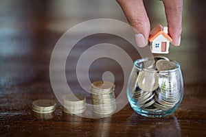 Human hand putting house model on coins stack. Concept for property ladder, mortgage and real estate investment