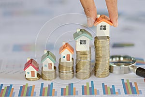 Human hand putting house model on coins stack. Concept for property ladder, mortgage and real estate investment