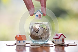 Human hand putting house model on coins stack, planning savings money of coins to buy a home concept, mortgage and real estate