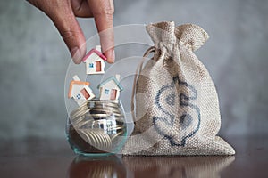 Human hand putting house model on coins stack, planning savings money of coins to buy a home concept, mortgage and real estate