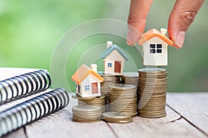 Human hand putting house model on coins stack,  planning savings money of coins to buy a home concept, mortgage and real estate