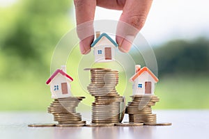 Human hand putting house model on coins stack,  planning savings money of coins to buy a home concept, mortgage and real estate