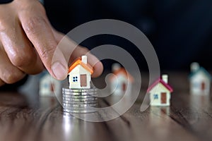 Human hand putting house model on coins stack,  planning savings money of coins to buy a home concept, mortgage and real estate