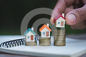 Human hand putting house model on coins stack,  planning savings money of coins to buy a home concept, mortgage and real estate