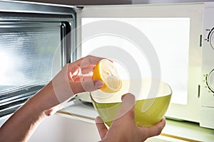 Human Hand Putting Sliced Lemon In Bowl