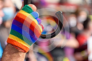 human hand in rainbow color glove. LGBT rainbow flag on foreground as a symbol of equality rights