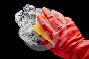 Human hand in a red rubber glove wiping with a sponge on isolated black background