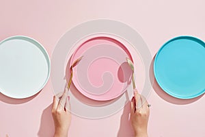 The human hand show gesture on an empty three color plates on a pink background