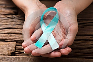 Human Hand Showing Teal Ribbon To Support Breast Cancer Cause