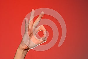 The human hand shows the sign ok symbolizing the positive, isolated on a red background