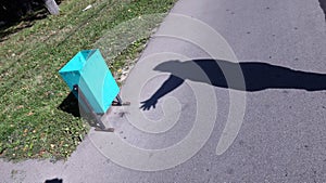 Human hand silhouette and green garbage urn on street under bright sunlight