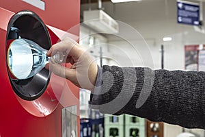 Human hand throws out a used plastic bottle in a recycling vending machine. Ecology concept