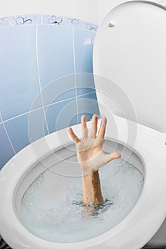 Human hand in toilet bowl or WC flushing and asking for help