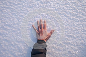 Human hand touches a white snowy surface