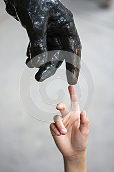 Human hand touching a statue