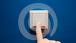 Human hand turn off a power button on a blue wall