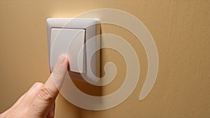 Human hand turn off a power button on a yellow wall - side view