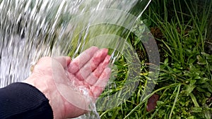 Human hand under a small waterfall. Close-up-a stream of water flowing down from a small waterfall. Soothing video. Refreshing the