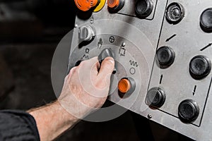 Human hand uses old control panel of industrial equipment in the factory